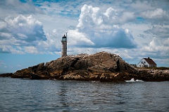 White Island Lighthouse Peaks Over Rocky Surface on Summer Day
